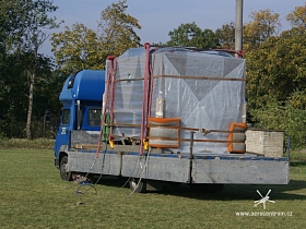 Vzduchotechnická jednotka připravená na korbě nákladního auta k vzdušnému transportu. Protože se bude zasouvat otvorem do budovy jsou na rozích matrace k ztlumení případného kontaktu se stěnou.  